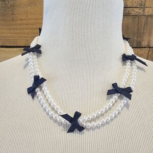 Double strand faux pearl necklace with navy grosgrain ribbon bows